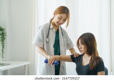 Asian Woman Physiotherapist Oversees The Patient’s Exercise.