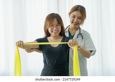 Asian Woman Physiotherapist Oversees The Patient’s Stretching With Elastic Tape.