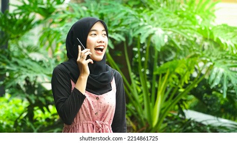 Asian Woman Picking Up Phone In Park