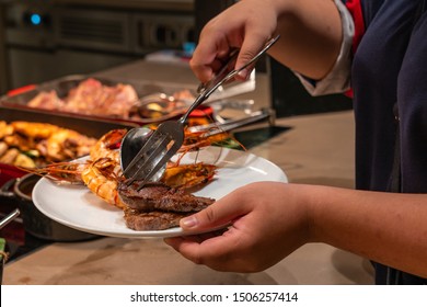 Asian Woman Picking Shrimps And Beef Steak At Buffet Meal