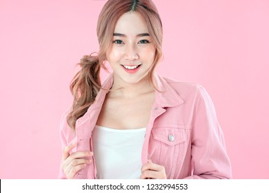 Asian woman with pigtail hair, jeans jacket clothing with backpack, pink background