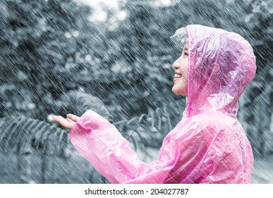 Asian woman in pink raincoat enjoying the rain in the garden - Shutterstock ID 204027787