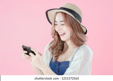 Asian woman play mobile game on smartphone, summer holiday clothing, pink background