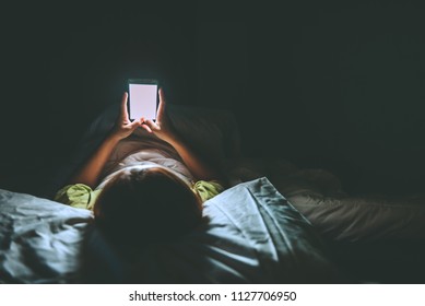 Asian woman playing game on smartphone in the bed at night,Thailand people,Addict social media - Shutterstock ID 1127706950