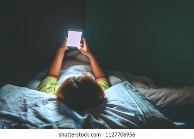 Asian woman playing game on smartphone in the bed at night,Thailand people,Addict social media - Shutterstock ID 1127706956