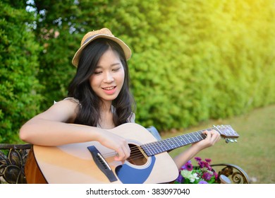 Asian Woman Playing Guitar  In The Garden