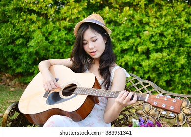 Asian Woman Playing Guitar In The Park