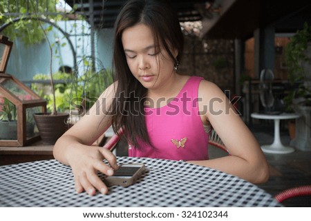 Asian woman playing smart phone in coffee shop