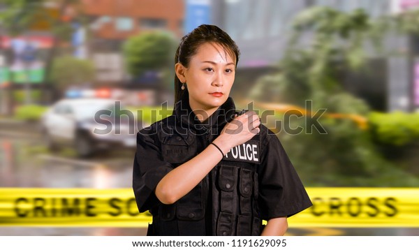 Asian Woman Police Officer at Crime scene Calling\
for Backup on CB Radio