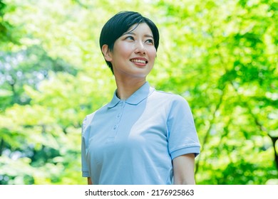 Asian Woman In A Polo Shirt Smiling And Laughing In The Fresh Green