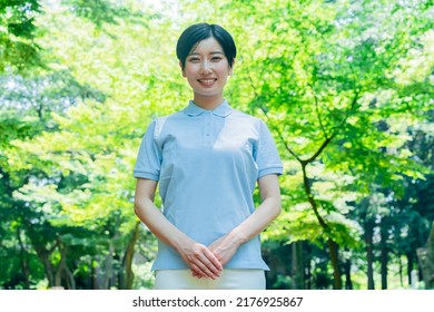 Asian Woman In A Polo Shirt Smiling And Laughing In The Fresh Green