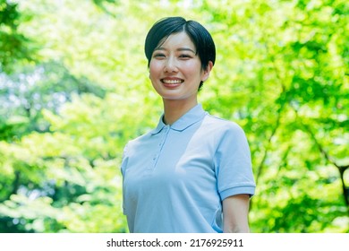 Asian Woman In A Polo Shirt Smiling And Laughing In The Fresh Green