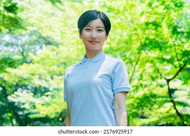 Asian Woman In A Polo Shirt Smiling And Laughing In The Fresh Green