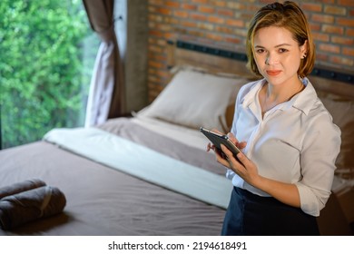 Asian Woman Portrait The Hotel Staff Is The Head Housekeeper Using A Tablet To Record The Cleanliness In The Hotel Room Before The Guest Enters The Room.