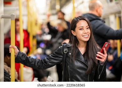 Asian Woman Portrait In The Tube Train Using Smartphone In London With Many People All Around, Busy Time At Rush Hour - Lifestyle And Travel Concepts