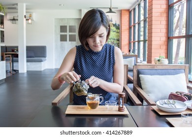 Asian Woman Pouring Tea Into A Glass