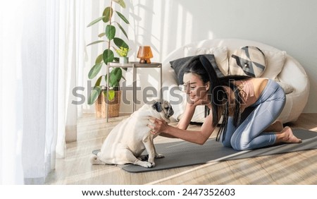 Asian woman practice yoga Downward with pug dog to meditation. Health care activities enjoy and relax with yoga.Smiling woman practicing yoga by dog on exercise mat at home recreation love concept