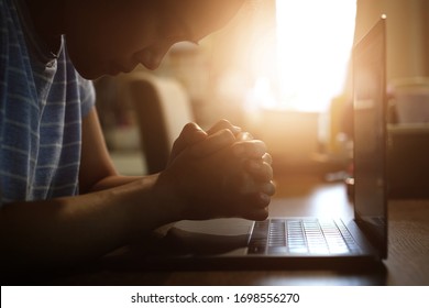 Asian woman praying in darkness with computer laptop ,Church services new normal concept, Home church during quarantine coronavirus Covid-19, Online church from home concept, spirituality and religion