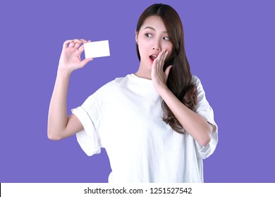 Asian woman present a blank credit card, white t-shirt clothing, purple background