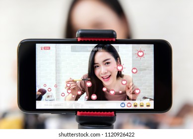 Asian woman professional beauty vlogger or blogger live broadcasting cosmetic makeup tutorial viral video clip by smartphone sharing on social media - Shutterstock ID 1120926422