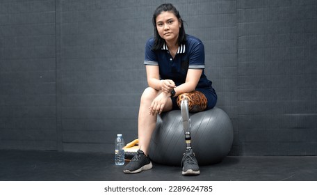 Asian woman with prosthetic leg lifting weight in gym. Young girl with foot prosthesis physical exercise in fitness. Artificial limb equipment help accident survivor or body injury people to mobility. - Powered by Shutterstock