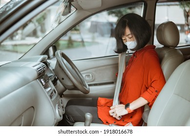 asian Woman in protective mask driving a car on road. Safe traveling and fasten seatbelt