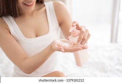 Asian Woman Is Pumping Out Body Lotion Or Cream From Pink Bottle After Take A Bath At Her Bedroom.