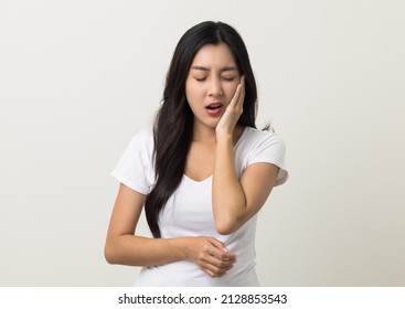 Asian Woman Puts Her Hand On Her Mouth And Feels Toothache Because Of Tooth Decay. Problems With Teeth Bad Breath. Asian Woman Around 25 Standing On Isolated Background