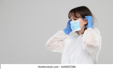 Asian Woman Puts On A Protective Mask And Suit. Protected Against Flu, Ebola, Tuberculosis, Virus. Personal Protective Equipment Against Biological Hazard. 