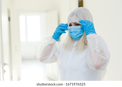 Asian Woman Puts On A Protective Mask And Suit. Protected Against Flu, Ebola, Tuberculosis, Virus. Personal Protective Equipment Against Biological Hazard.