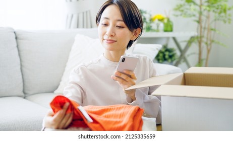 Asian Woman Putting Clothes Away In A Box