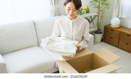 Asian Woman Putting Clothes Away In A Box