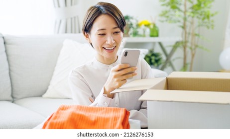 Asian Woman Putting Clothes Away In A Box