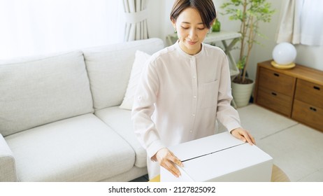 Asian Woman Putting Clothes Away In A Box