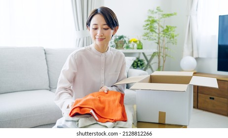 Asian Woman Putting Clothes Away In A Box