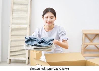Asian woman putting things in cardboard boxes at the living room - Shutterstock ID 2237253995