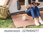 Asian woman reading a book enjoying camping outdoors in nature. traveling in the wild