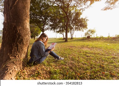 Asian Woman Reading A Book Under The Tree.