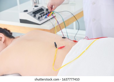 Asian woman receiving acupuncture with electrical stimulator at back ,Alternative medicine concept.
