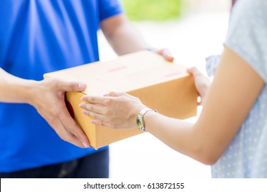 Asian Woman Receiving A Package At Home From A Delivery Guy