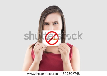 Asian woman in red blouse is holding no smoking sign on the white paper against gray background. Picture of the woman with a smoking restriction sign. Warning about the harm of tobacco use. 商業照片 © 