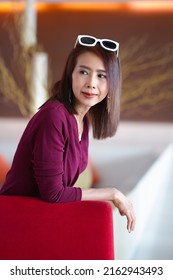 Asian Woman In Red Dress In Modern Corporate Building Lobby.