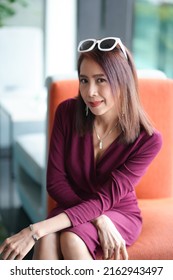 Asian Woman In Red Dress In Modern Corporate Building Lobby.