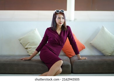 Asian Woman In Red Dress In Modern Corporate Building Lobby.