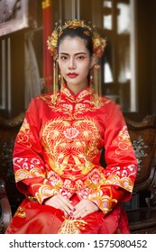 Asian woman in red traditional chiness dress sit on wooden bench,opera chinese.  - Shutterstock ID 1575080452