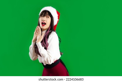 Asian Woman In Red And White Clothes Wear Santa Hat Posing Surprised Face On Green Screen Background.