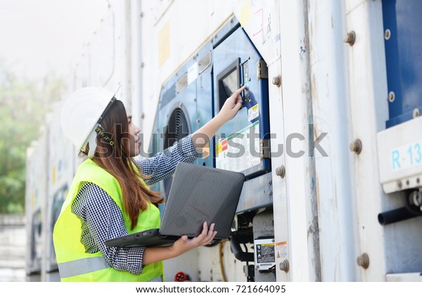 Asian woman as\
in reefer container technician is monitoring the temperature by\
using computer at the\
port.