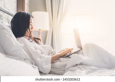 Asian Woman Relaxing In The Hotel Room And Working On Labtop, Copy Space