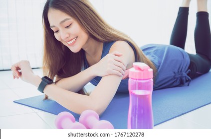 Asian Woman Resting And Using Smart Watch After Play Yoga And Exercise At Home Background With Copy Space.Concept Of Sport Technology To Checking Health Data.