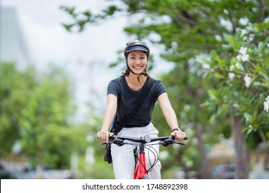 Asian woman ride bikes to work she is happy and safe.